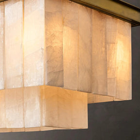 A close-up shot of a Shopp578 Natural Calcite Dining Room Chandelier featuring rectangular, semi-translucent white shades. The brass accents complement the warm, soft glow that emits through the shades, creating an inviting ambiance against a dark background.