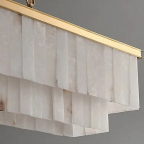 A close-up of a Shopp578 Natural Calcite Dining Room Chandelier with cascading rectangular white panels and a brass frame. The design features multiple layers of translucent natural calcite panels that create a stylish and elegant look against a plain gray background.