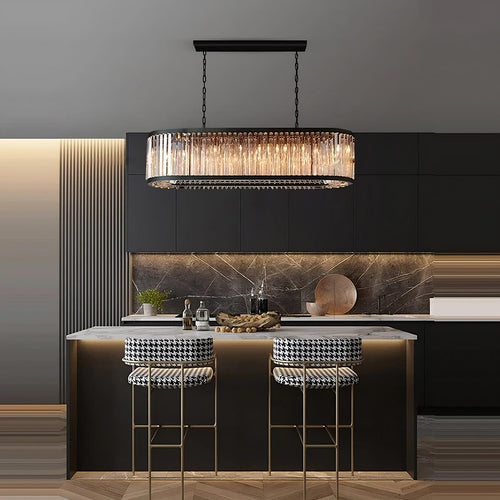 A modern kitchen with dark cabinets, marble backsplash, a white island countertop, and two houndstooth barstools. The Gio Amber Crystal Dining Chandelier by Morsale.com with dimmable lighting hangs above, perfect for contemporary interiors.