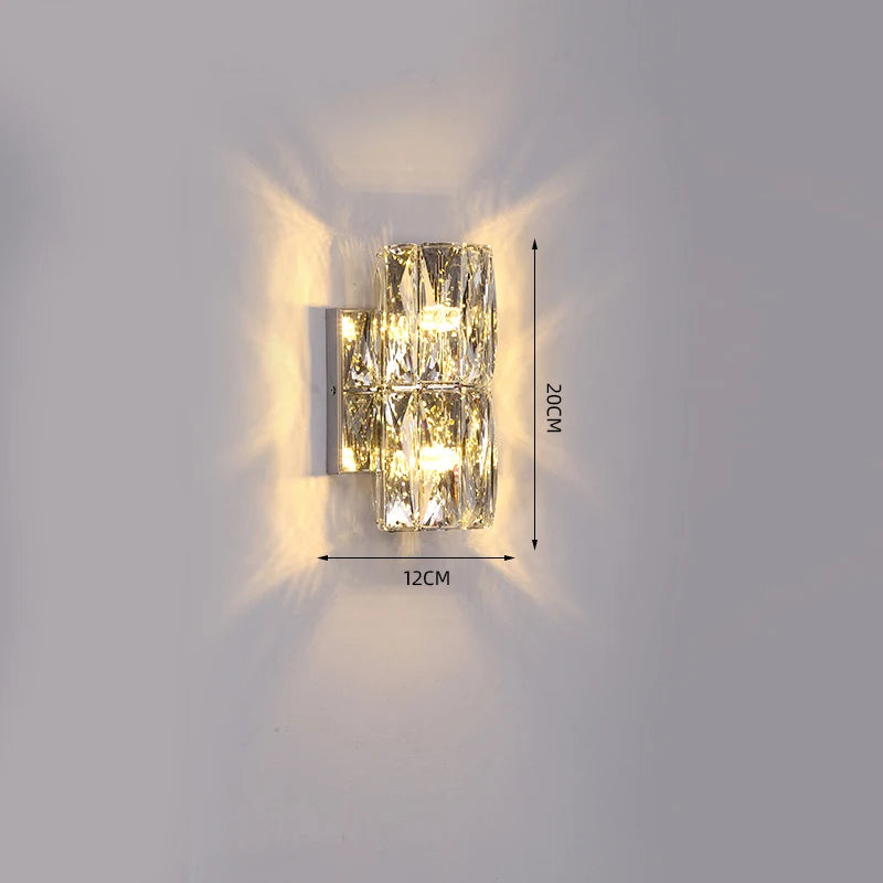 The Bacci Crystal Wall Light Sconce by Morsale.com is a modern wall light fixture adorned with two crystal-like blocks that emit a glowing light. This handmade crystal indoor wall sconce measures 12 cm in width and 20 cm in height, as indicated in the image. Mounted on a plain, light-colored wall, it features LED dimmable technology for adjustable ambiance.