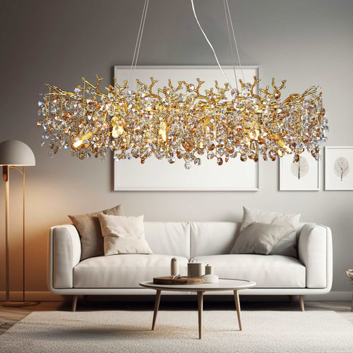 A modern living room with a white sofa, neutral cushions, a round coffee table, and striking statement lighting from Morsale.com’s Albero Crystal Dining Chandelier. Light gray walls feature minimalist framed art for a chic look.