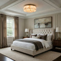 Neatly made bed in a bedroom with a painting on the wall and a lamp on a nightstand.