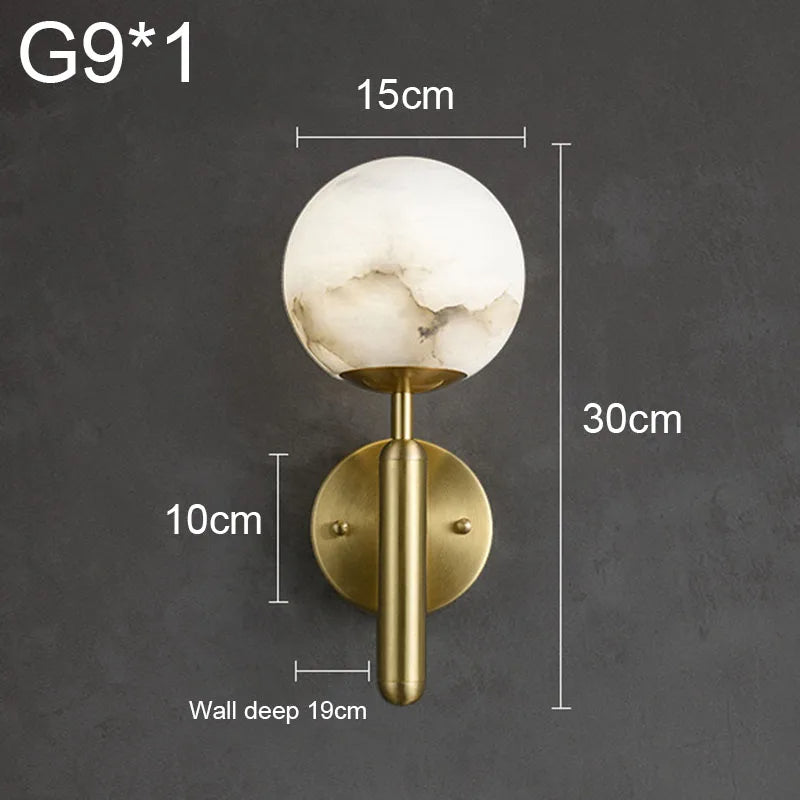 A Natural Marble Sphere Wall Sconce by Morsale.com with a globe-shaped natural marble light and a gold base is shown. The unique texture adds an elegant touch. Dimensions: height 30cm, width 15cm, depth from wall 19cm. The globe light itself is 10cm in diameter and requires a G9-type bulb for the brass light source.