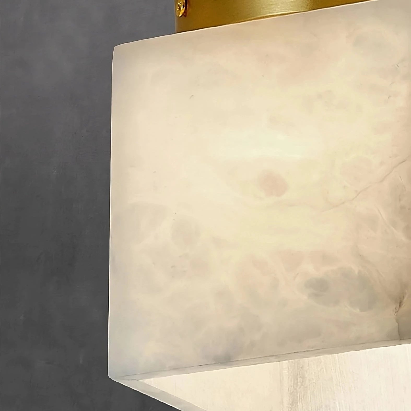 Close-up image of a square, frosted glass Natural Marble Hallway Ceiling Light Fixture by Morsale.com with a brass accent. The background is a smooth, dark grey surface, which contrasts with the light's soft, diffused glow.