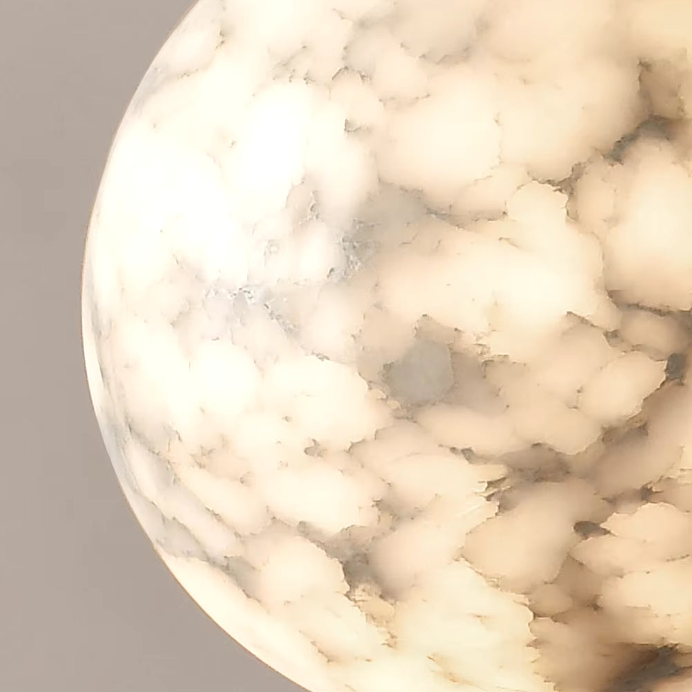 A close-up view of the Moonshade Natural Marble Ball Pendant Light by Morsale reveals its spherical design, showcasing a creamy marble-like surface with intricate white and gray swirls. This modern texture resembles cloud formations or soft, flowing patterns, emitting an elegant glow when enhanced with LED bulbs.