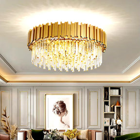 In a luxurious living room, a Gio Flush Mount Chandelier by Morsale.com graces the ceiling with its gold-plated stainless steel structure and exquisite handmade K9 crystals. The space features elegant gray paneled walls, a large framed portrait, and a cozy seating area with pillows, while seamlessly integrated bookshelves enhance the design.