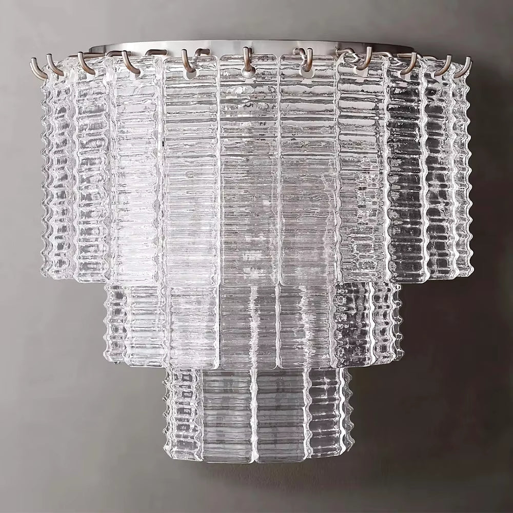 The Palermo Clear Crystal Wall Sconce by Chandelier Style features rectangular, textured glass panels set in a layered design under a metal frame. This sophisticated sconce blends contemporary style with luxurious crystal accents, highlighting geometric shapes and transparency.