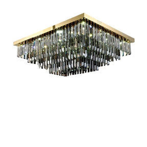Introducing the Gio Smoke Grey Crystal Ceiling Chandelier by Morsale.com: A square chandelier with a gold frame and multiple hanging smoke grey crystal prisms in varying lengths. The crystals reflect light, creating a dazzling effect. The fixture is mounted flush to the ceiling, with the overall design giving an elegant and luxurious appearance.
