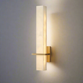 The Natural Marble Indoor Sconce from Morsale.com features a modern design with a slim, rectangular marble shade and a brass mounting base. It includes an LED light source that emits a warm glow and is positioned vertically on a neutral-colored wall.