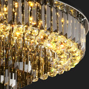 A close-up view of the sophisticated Gio Crystal Ceiling Light by Morsale.com showcases its smoke grey crystals and spherical ornaments. The chandelier casts a warm, golden glow that reflects off the crystals, producing a dazzling, opulent atmosphere against a dark background.
