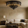 Elegant living room with a beige sectional, dark wood tables, glass lamp, and the Gio Flush Mount Chandelier by Morsale.com. The modern chandelier's smoke grey crystals enhance the light tan tiled walls beautifully.