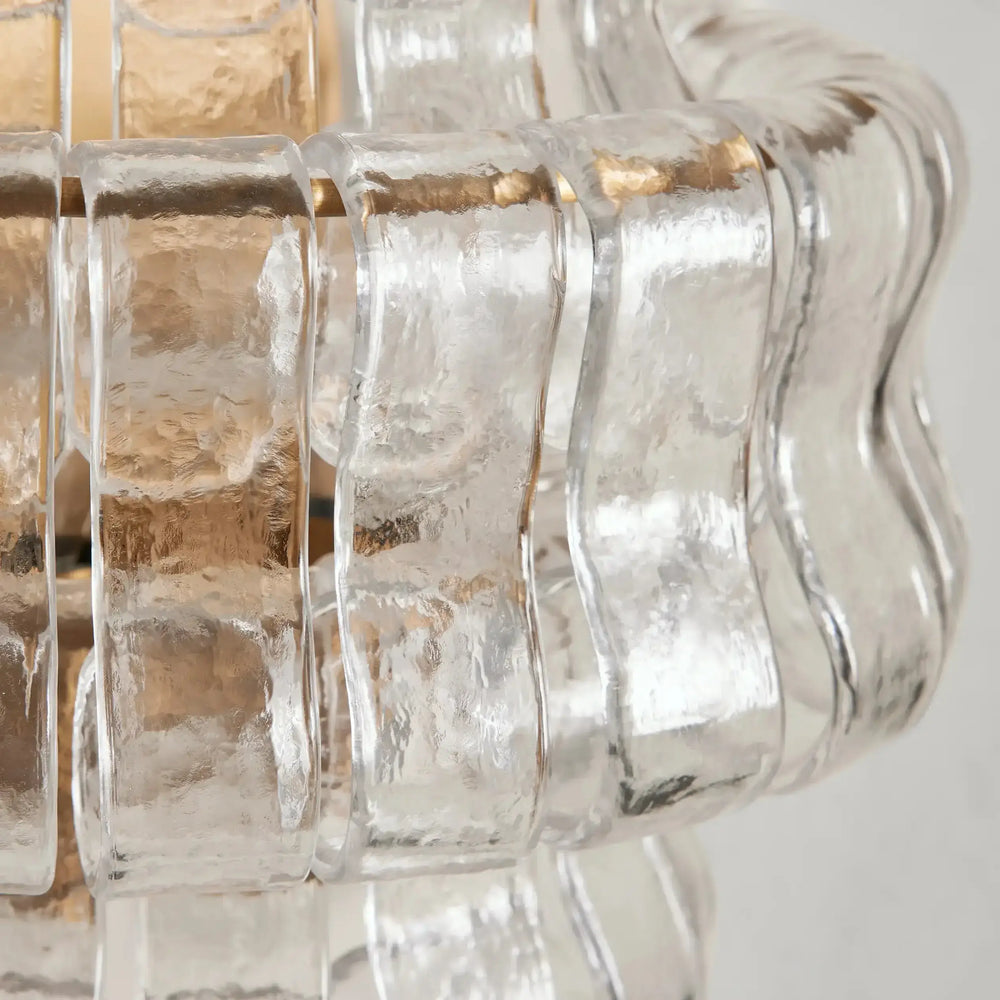 
                  
                    The Riviera Sconce by Morsale.com features textured, wavy glass panels with clear and frosted elements, artfully arranged in a circular design around a light source for a modern, sculptural wall lighting fixture.
                  
                