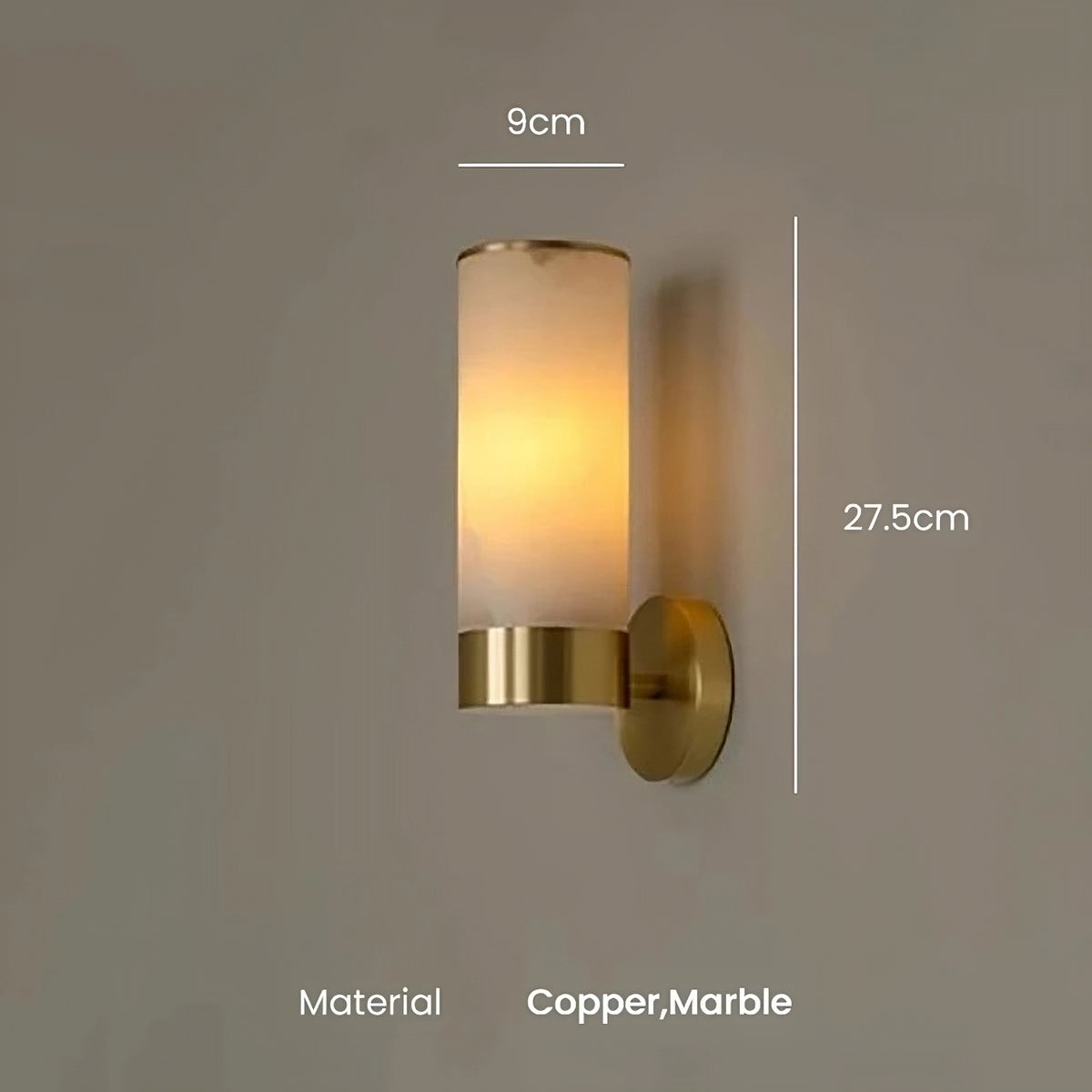 The Moonshade Natural Marble Sconce Light from Morsale.com features a cylindrical design with a frosted glass shade, emitting a warm glow. Crafted from genuine marble and copper, it stands 27.5 cm tall and measures 9 cm wide. Equipped with an E14 Base LED, it is beautifully set against a plain, neutral-colored wall.