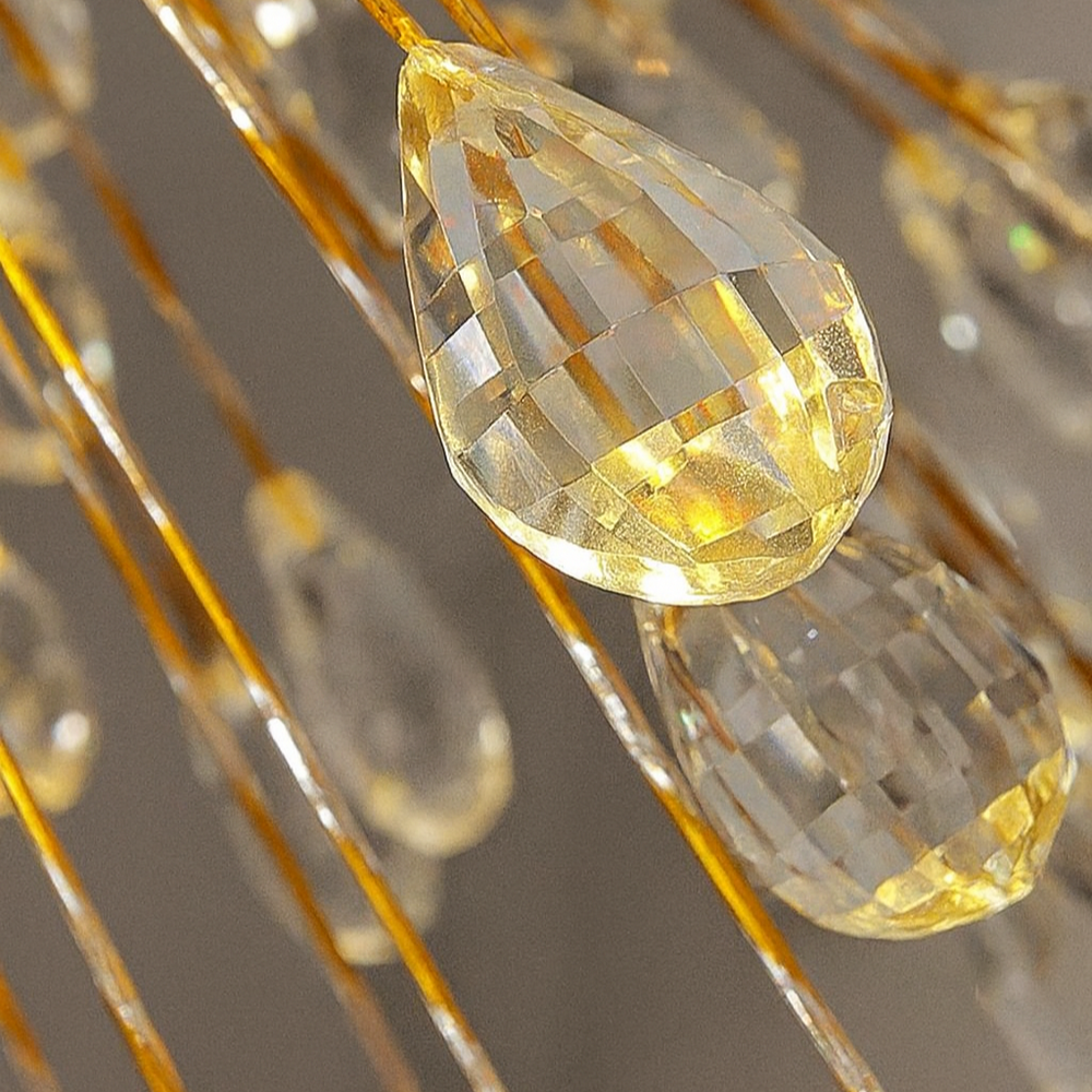 
                  
                    Close-up of teardrop-shaped, yellow-tinted crystals on golden wires—a detail from the Morsale.com Vanci Crystal Globe Chandelier—reflecting light and creating a sparkling effect against a neutral background.
                  
                
