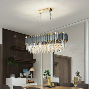 Modern dining room featuring a large, Gio 39" Crystal Dining Room Chandelier from Morsale.com with angular, metallic accents and dangling crystals. The elegant design includes a wooden dining table with potted plants and golden décor items, dark wood shelving, a mirrored wall, and minimalist furnishings.