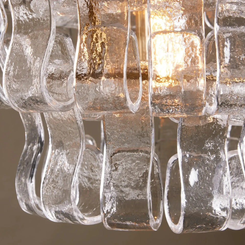 
                  
                    The Morsale Riviera Pendant features vertically arranged, textured wavy glass panels illuminated by a warm glow, creating sleek reflections and an elegant, modern look.
                  
                