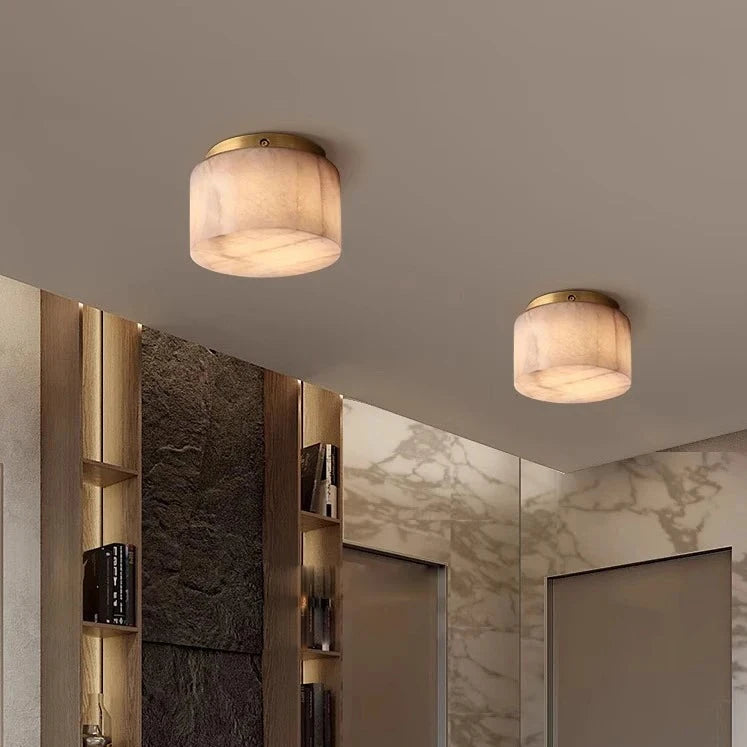 A modern minimalist hallway featuring two energy-efficient Moonshade Natural Marble Ceiling Light Fixtures from Morsale.com, wooden shelves with books and decor on the left, and a mix of stone and natural marble walls. Two closed doors are visible at the end of the corridor.