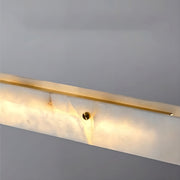 The 60" Natural Marble Dining Room Light Fixture by Morsale is mounted on a plain, light gray wall, emitting a warm glow. This luxurious design features a sleek, modern LED light fixture with a rectangular slab of natural marble and a brass accent, enhancing its elegant and minimalist appeal. Ideal for use as a durable dining room light fixture.