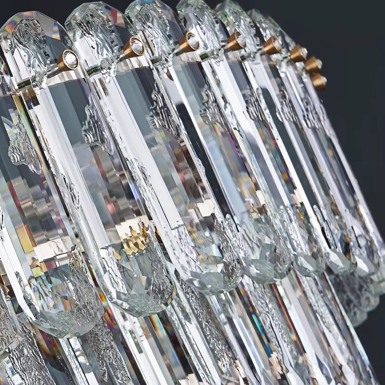 A close-up of the elegant Gio Crystal Chandelier by Morsale showcases intricate designs, featuring elongated crystals arranged in a row. Enhanced by LED bulbs, this chandelier reflects light to create a sparkling effect against a dark background, adding a touch of modern style.