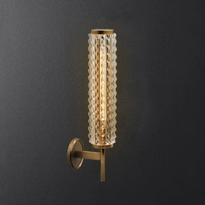 The Crystal & Copper Contemporary Wall Sconce from Morsale.com features a wall-mounted, LED wall light with a textured cylindrical glass shade that emits a warm glow. Its metallic base and arm boast a brushed brass finish, creating an appealing contrast against the dark gray wall background. This design seamlessly blends contemporary aesthetics with vintage elegance.