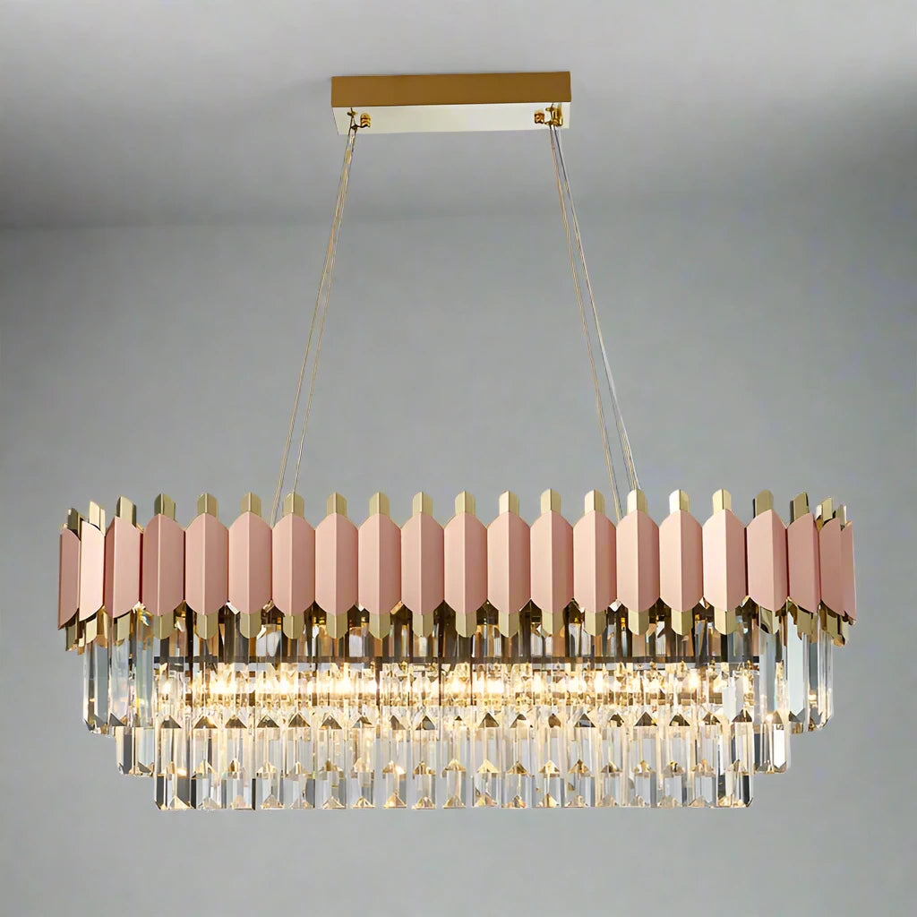 The Gio 39" Rose Gold Dining Room Chandelier by Morsale.com, a luxurious rectangular fixture, features a gold and rose gold frame with multiple tiers of hanging glass prisms. Suspended by two stainless steel cables from a gold ceiling mount, it emits a warm, elegant glow against a plain gray background. The chandelier includes dimmable LED lights.