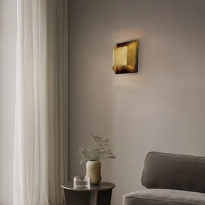 A modern living room with a minimalist aesthetic features home decor lighting that includes the Morsale Rame Modern Copper Wall Lights, providing soft illumination. A gray couch sits near a small round table adorned with a vase of greenery, while sheer white curtains cover the large window, enhancing the serene atmosphere.