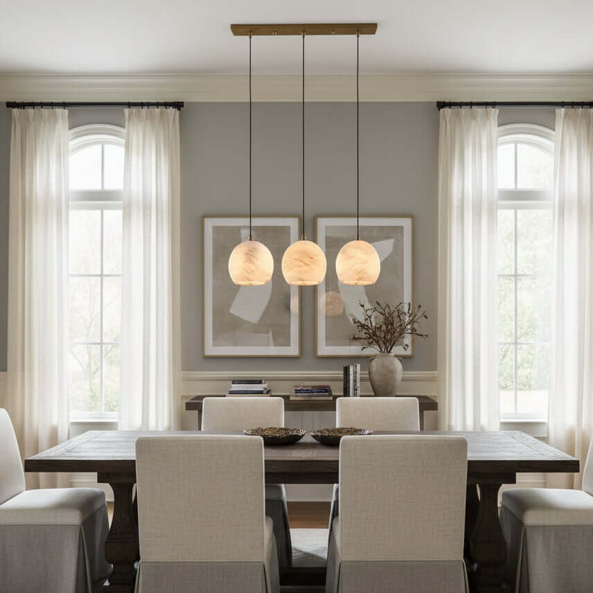 A modern dining room features a dark wooden table, six upholstered chairs, and the Auris 3-Light Linear Marble Chandelier by Morsale.com, illuminating light gray walls, abstract art, and large windows with sheer white curtains.