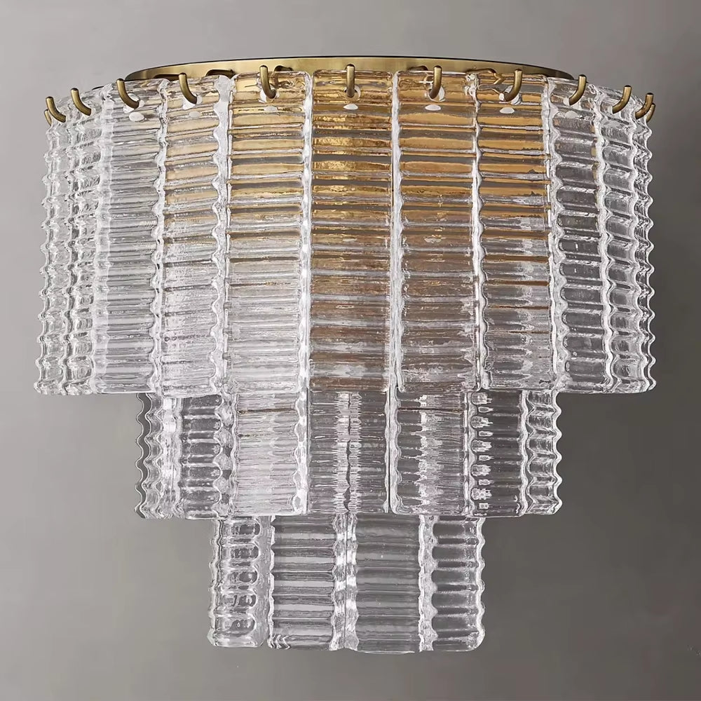 The Palermo Clear Crystal Wall Sconce by Chandelier Style features ribbed, rectangular segments with a brass base, creating an elegant and modern aesthetic against a gray background. Luxurious crystal accents further enhance its sophistication.