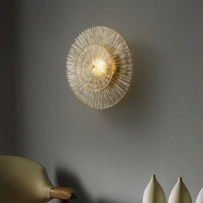 A Modern Glass Wall Sconce by Morsale.com illuminates against a gray wall. Below the light, a minimalist chair is partially visible on the left, while two white ceramic vases of different heights are arranged on the right.