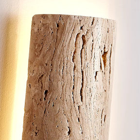 A detailed view of the IP65 Waterproof Natural Travertine Wall Light by Morsale, showcasing its textured cylindrical design. This wall sconce, featuring LED lighting, exudes a gentle glow that accentuates the natural grooves and patterns of the stone.