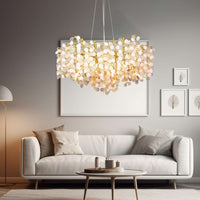 A modern living room featuring a white sofa, neutral cushions, a round coffee table, and the Albero Frost Glass Modern Chandelier by Morsale.com. Minimalist wall art and a floor lamp add to the cozy, sophisticated vibe.