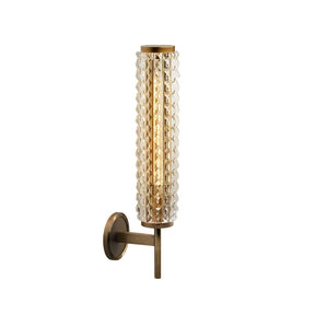 The Crystal & Copper Contemporary Wall Sconce from Morsale.com is a wall-mounted light fixture with a cylindrical glass shade featuring a textured, diamond pattern. This modern design piece emits a warm LED wall light and is attached to a vertical bronze-colored support with a round base.