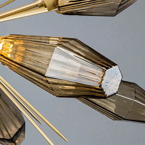 Close-up of the Morelli Sputnik Chandelier by Morsale.com featuring elongated, hexagonal glass elements with amber tint. The borosilicate glass pieces are arranged in a radial pattern, extending from gold-colored metal rods, creating a sophisticated and elegant lighting fixture.