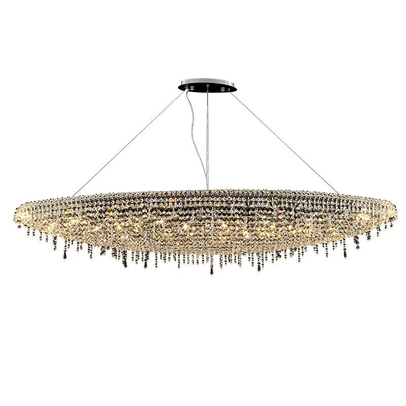 The Alleri Crystal Chandelier For Dining Room by Morsale.com is a large, oval-shaped fixture that gracefully hangs from the ceiling with thin wires. It boasts numerous small, handmade crystals that create a shimmering effect, with some crystals elegantly hanging down in strands. The sophisticated design is illuminated by E14 LED bulbs for a dazzling display.