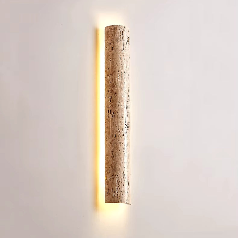 The IP65 Waterproof Natural Travertine Wall Light by Morsale is a wall-mounted cylindrical sconce featuring LED illumination. Crafted from textured stone, it emits a soft, warm light that emphasizes its natural surface. Its gentle glow enhances a plain white wall, adding to an elegant and modern design ambiance.