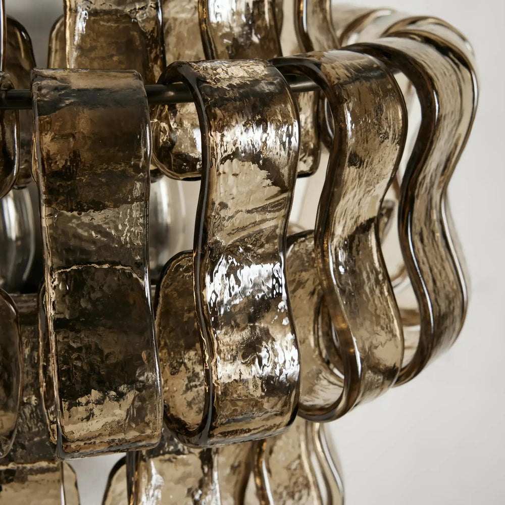 
                  
                    Close-up of the Riviera Sconce by Morsale.com: metallic, wavy, ribbon-like strips with a hammered, reflective surface and bronze-tinted layers create an abstract pattern, showcasing sculptural artistry in this luxury interior lighting fixture.
                  
                