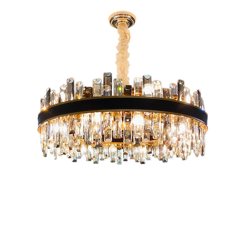 The Calvi Modern Chandelier by Morsale.com features a round, black frame adorned with numerous hanging crystal prisms. The crystals refract light, creating a shimmering effect. This luxury lighting fixture is suspended from a bronze-colored ceiling mount with a textured, beige cord.