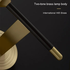 A close-up view of a two-tone brass lamp body with a combination of matte black and polished brass finishes. The text "Two-tone brass lamp body," "International H65 Brass," and "Palermo Wall Sconce Light" are displayed on the right side of the image. The product is by Morsale.

