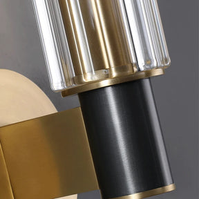 Close-up of the Morsale Palermo Retro Brass Wall Sconce featuring a black cylindrical base, a brass-colored vertical support, and a clear textured glass globe. The design combines metallic elements with transparent glass, showcasing an elegant and contemporary aesthetic.