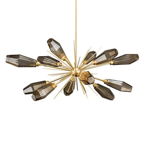 A Morsale.com Morelli Sputnik Chandelier with a gold metallic frame and elongated, smoke-colored glass shades. The fixture features multiple arms extending outward in a starburst pattern. Each arm holds an LED light bulb enclosed within the tinted glass shades.