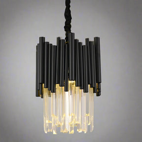 The Vigo Kitchen Island Light Fixture from Morsale.com showcases a sleek series of black cylindrical rods complemented by handmade clear crystals. These crystals diffuse light beautifully, casting a warm glow against a grey backdrop. Suspended from a premium stainless steel cord, this fixture brings an elegant touch to any space.