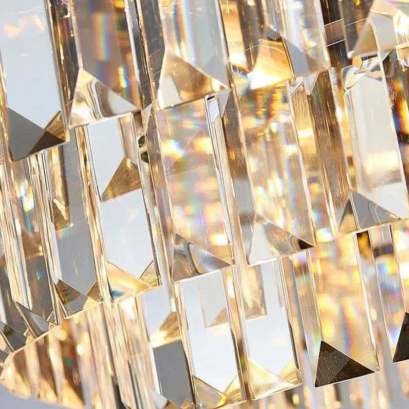 Close-up of hanging handcrafted crystal prisms reflecting light, creating a shimmering effect in various shades and colors. The prisms are rectangular with faceted edges, arranged in a cascading pattern on a gold plated stainless steel frame. This is the Gio Rose Gold Modern Chandelier by Morsale.com.