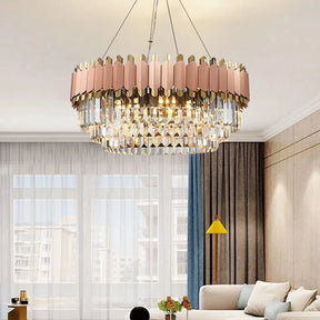 Modern living room with a large, colorful Gio Rose Gold Modern Chandelier from Morsale.com hanging from the ceiling above a round coffee table. The room features white sofas, a blue and yellow rug, a gold and yellow floor lamp, and large windows with sheer curtains, allowing natural light to fill the space.