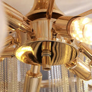 Close-up of a modern gold chandelier by Morsale.com, featuring multiple cylindrical light fixtures extending outwards with warm light emitting from them. This luxurious Cadena Chain Tassel Ceiling Light reflects beautifully off its shiny metallic surface, embodying the essence of modern elegant lighting.