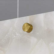 A close-up image of a Morsale metal rod and brass cap clamp holding a piece of smooth, translucent material. The material has a frosted, marbled texture, reminiscent of the 60" Natural Marble Dining Room Light Fixture by Morsale. The durable construction ensures the clamp is securely fastened near the top edge against the plain, gradient gray background.
