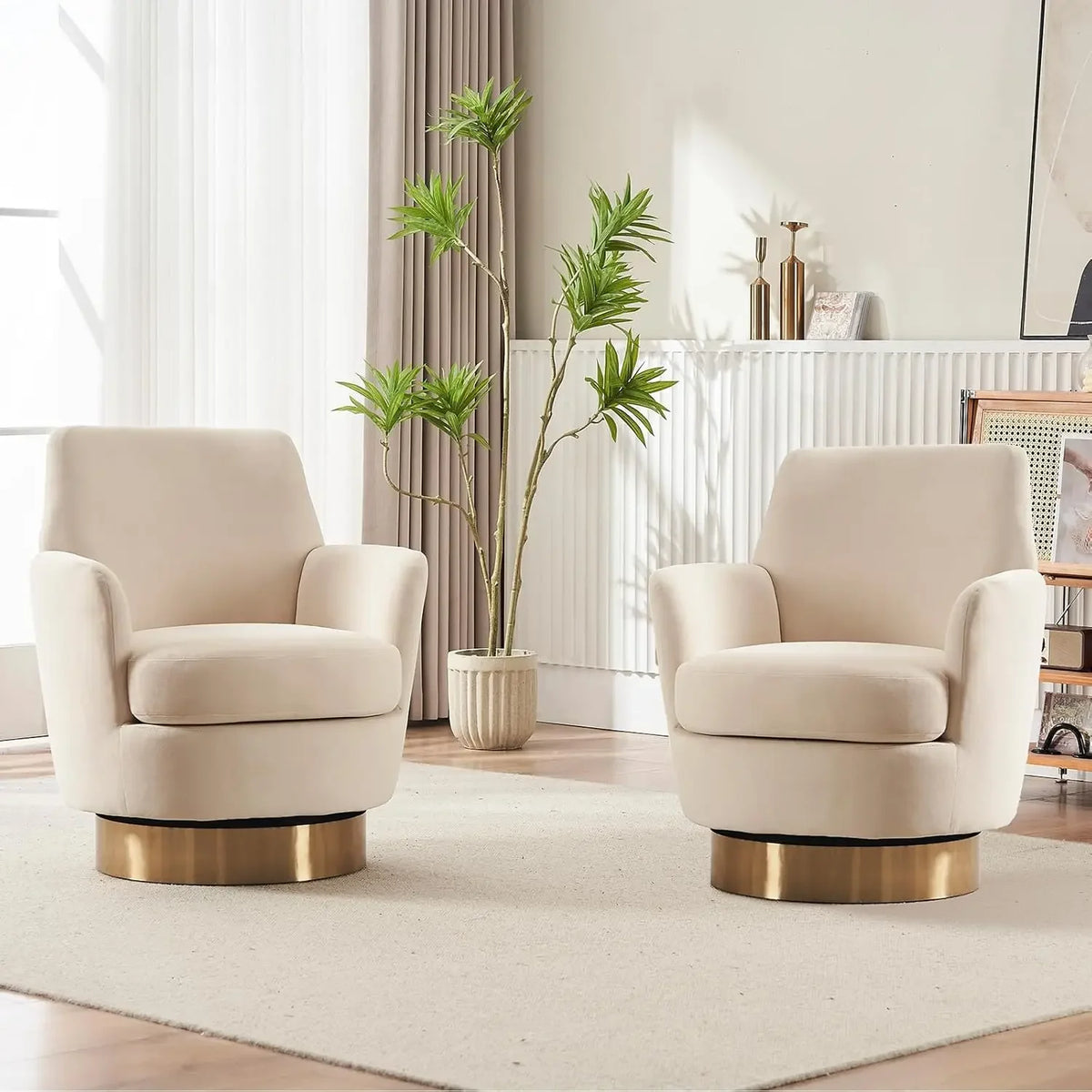 In a living room, two Morsale velvet swivel lounge chairs with gold bases sit on a light rug. A potted plant is placed between them as sunlight streams through sheer curtains, softly highlighting their quality upholstery.