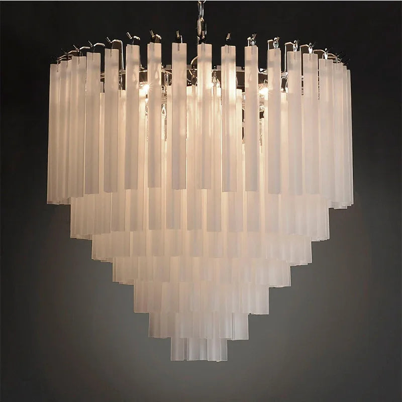 The Frost White Crystal Chandelier by Morsale, featuring a tiered design with frosted glass panels illuminated by LED bulbs, hangs from the ceiling as an elegant and luxurious lighting fixture against a dark background.