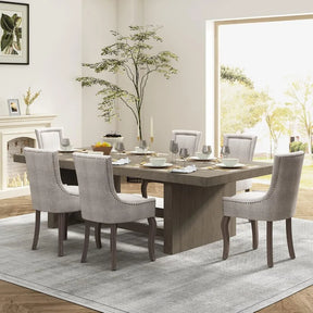 This dining room features a rectangular wooden table and Morsale's Chester Dining Chairs Set Of 6 in sleek light gray upholstery. A plant adorns the corner, with natural light enhancing the light-colored walls and large gray rug, adding to the elegant ambiance.