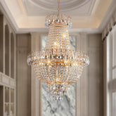 The Morsale French Empire Crystal Chandelier, an elegant piece with halogen bulbs, hangs from a high ceiling in a sophisticated room. Its crystal decorations cast a warm glow as they reflect light beautifully.