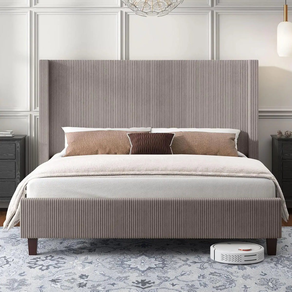A spacious bedroom features the Morsale Corduroy Bed With Wingback Headboard, adorned with a thick white comforter and brown accent pillows. Two bedside tables accompany it, with a robotic vacuum humming beneath the durable hardwood floor as decorative lighting hangs above.